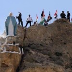 أفراد من قوات الدفاع الوطني يقفون خلف تمثال جديد للسيدة العذراء يشرف على بلدة معلولا، على 56 كيلومترا شمال شرق دمشق، أول من أمس. (أ ف ب)